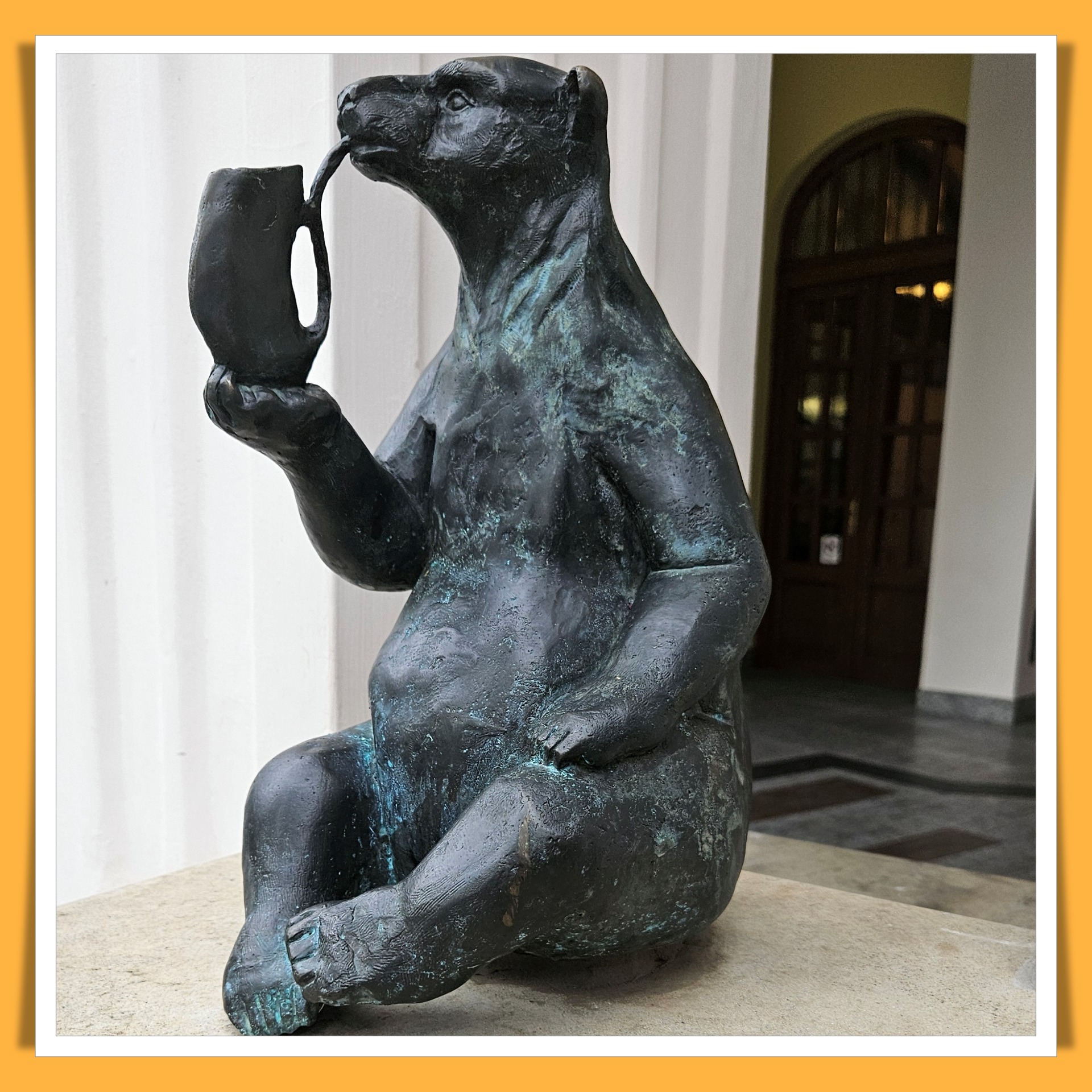 Miś z pijałką siedzący przy wejściu dopijalni